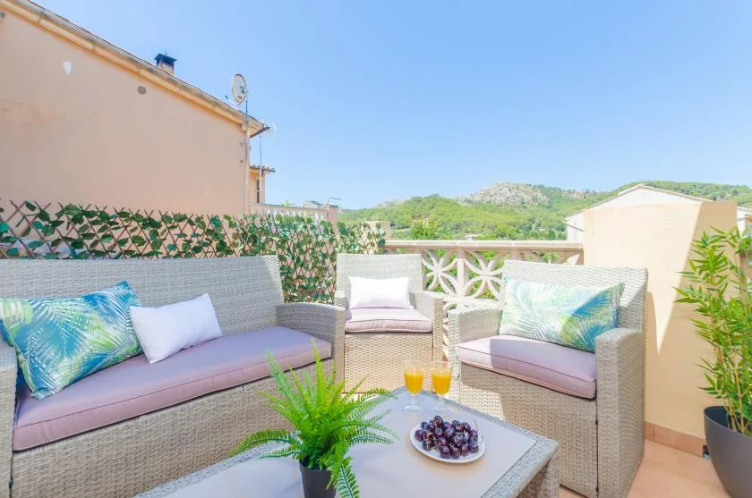 Una terraza en la azotea con asientos al aire libre, plantas en macetas y vistas a colinas verdes.