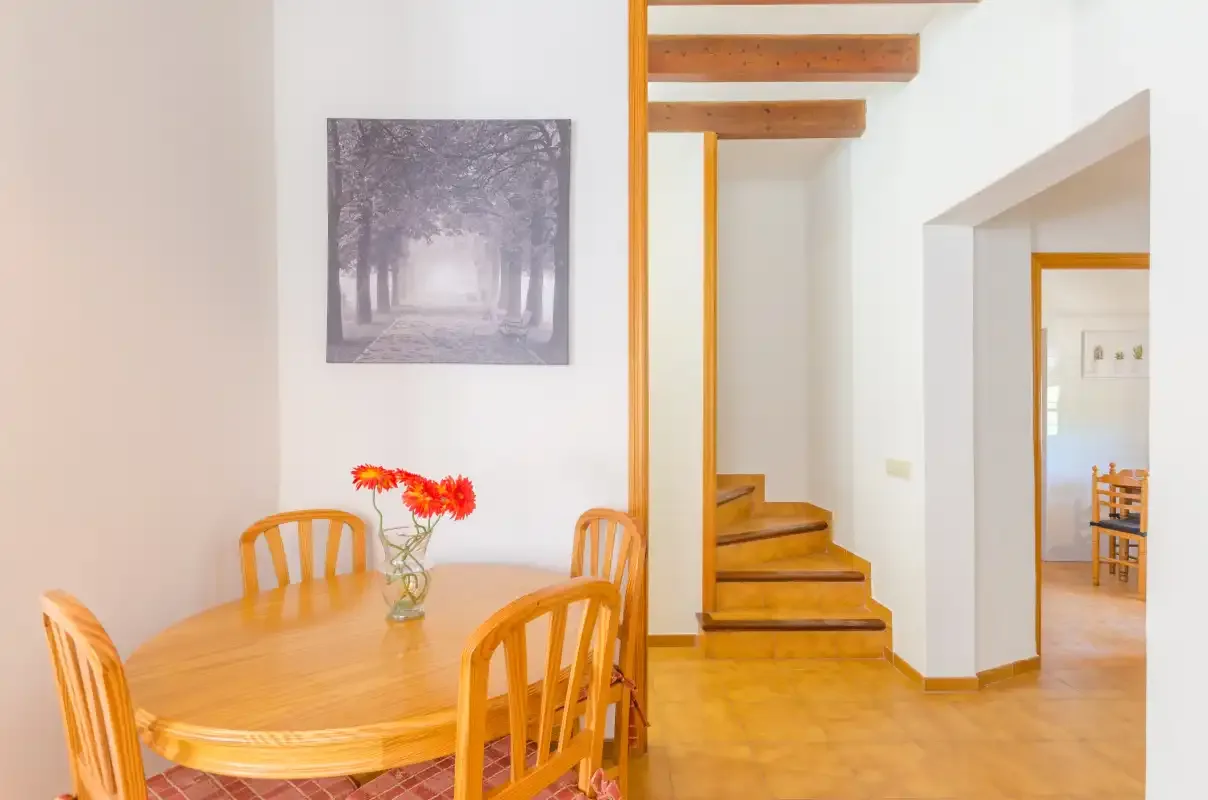 A dining area with a wooden table and chairs beside a staircase.