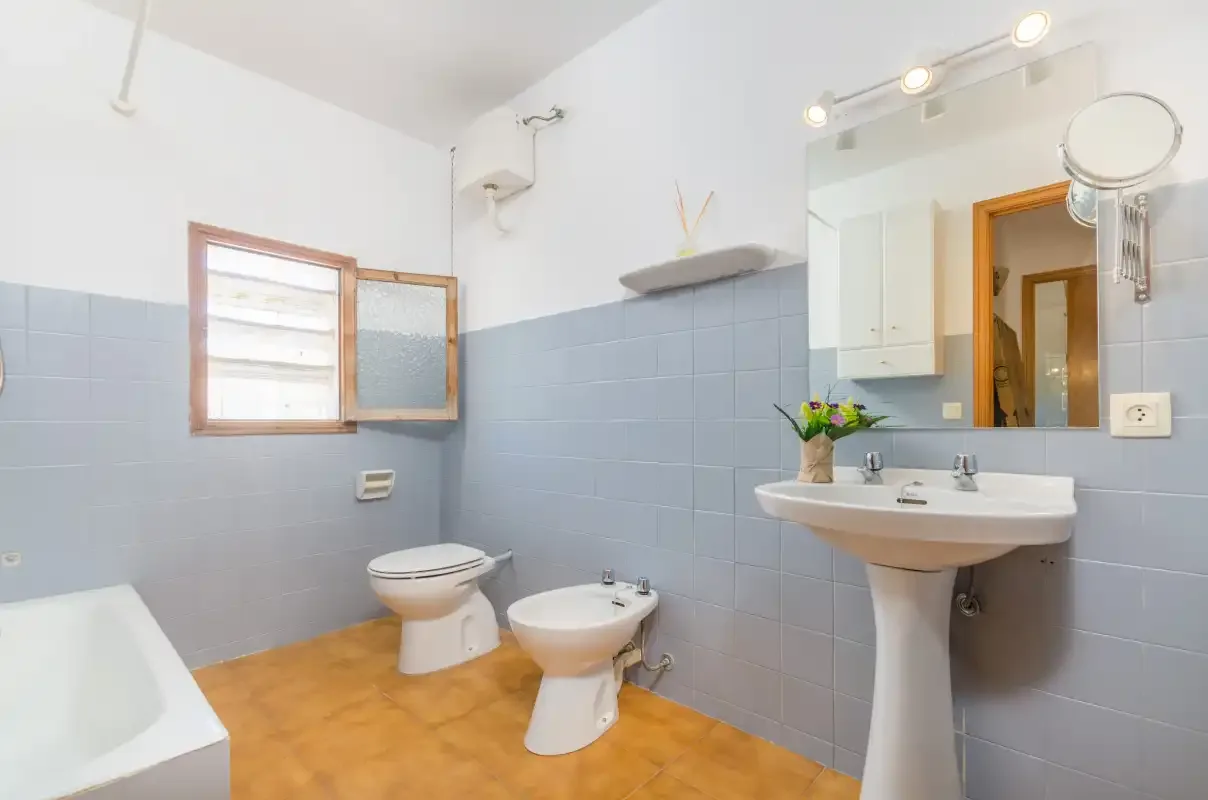 A bathroom with a bathtub, toilet, bidet, and sink beneath a large mirror.