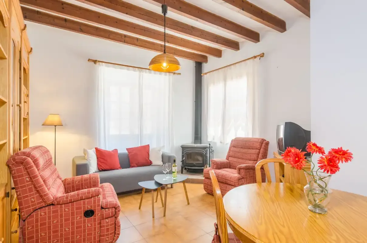 A living room with seating, a wood dining table, and exposed ceiling beams.