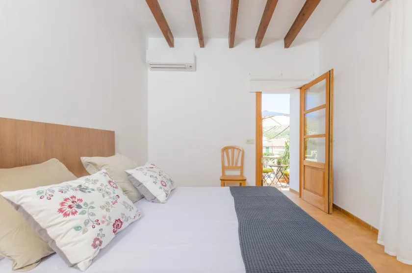 A bedroom with a bed, floral pillows, and an open wooden door.