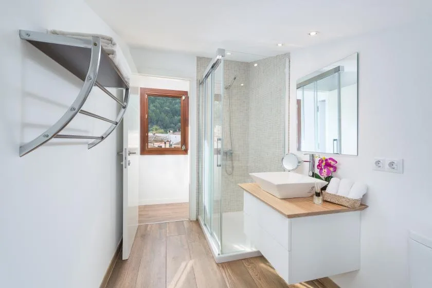 A bright bathroom with a glass shower and a sink vanity.