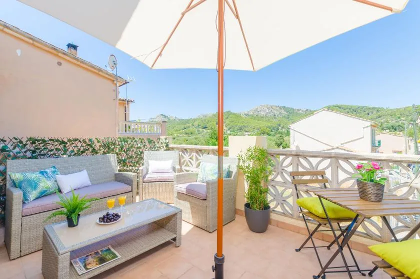 An outdoor patio with seating, a table, and views of green hills.