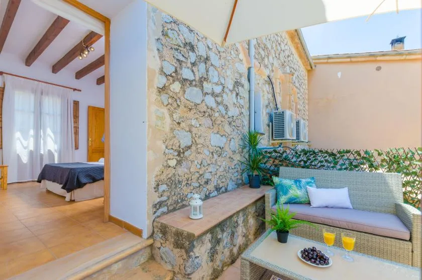 A stone patio with outdoor seating sits beside a bedroom doorway.