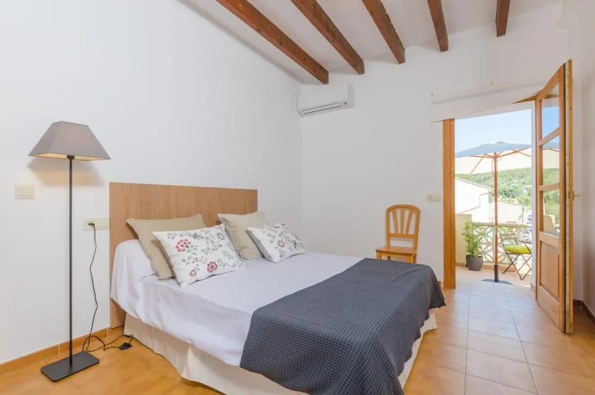 A bedroom with a bed and an open doorway leading to a balcony.
