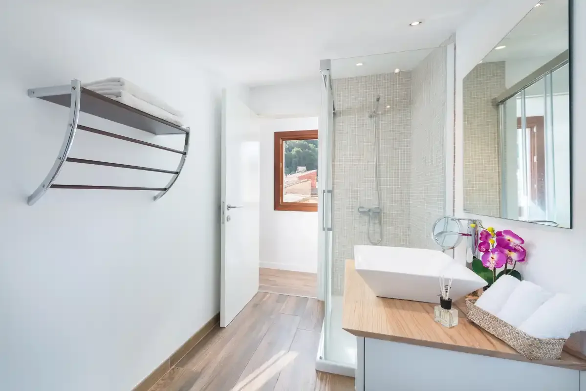 A bright bathroom with a glass shower and a vessel sink.