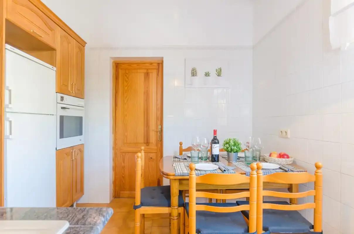A dining area with a wooden table beside the kitchen cabinetry.