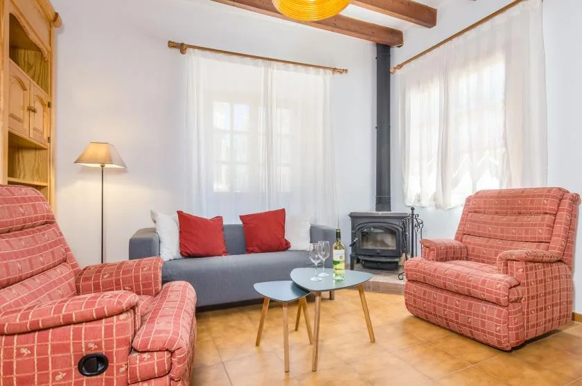 A bright living room with seating, a small table, and a wood-burning stove.