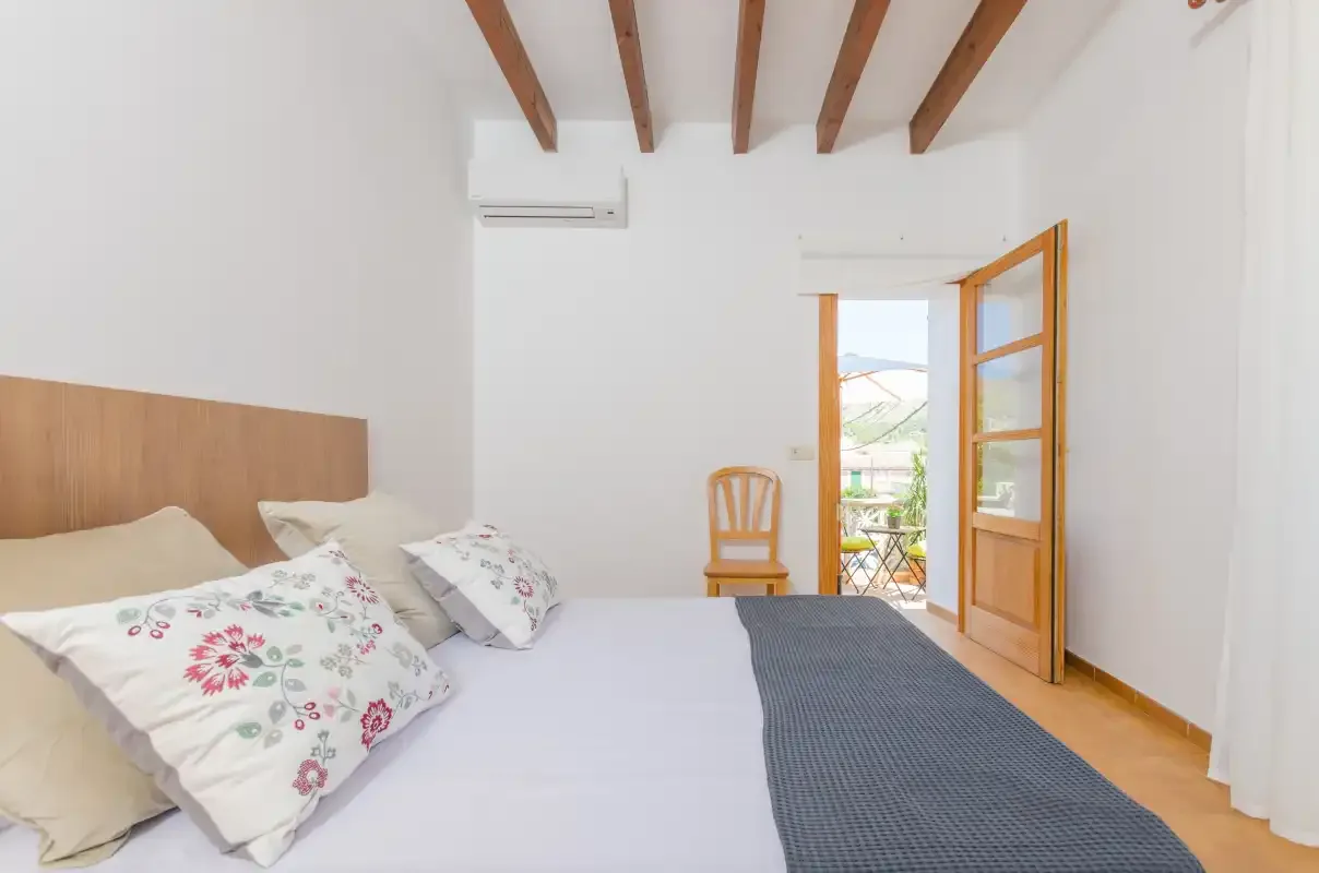 A bedroom with a bed and an open wooden door to a balcony.