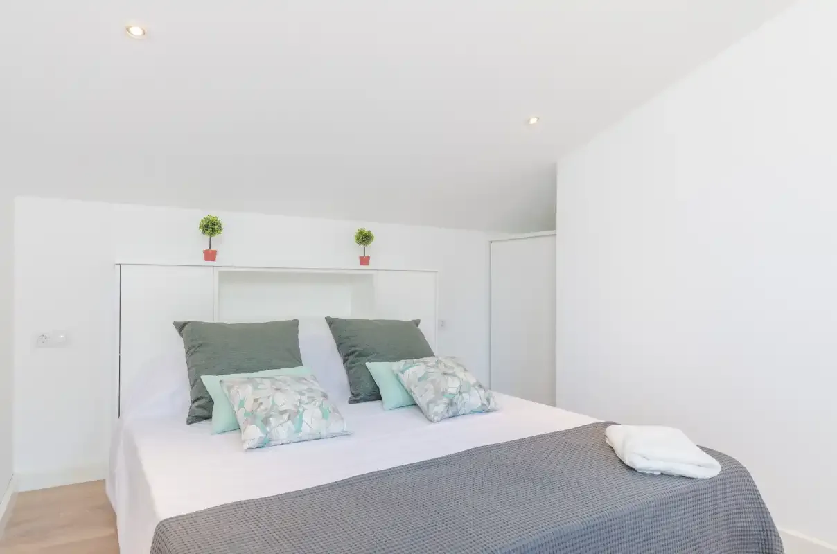 A bright bedroom with a large bed and white bedding.