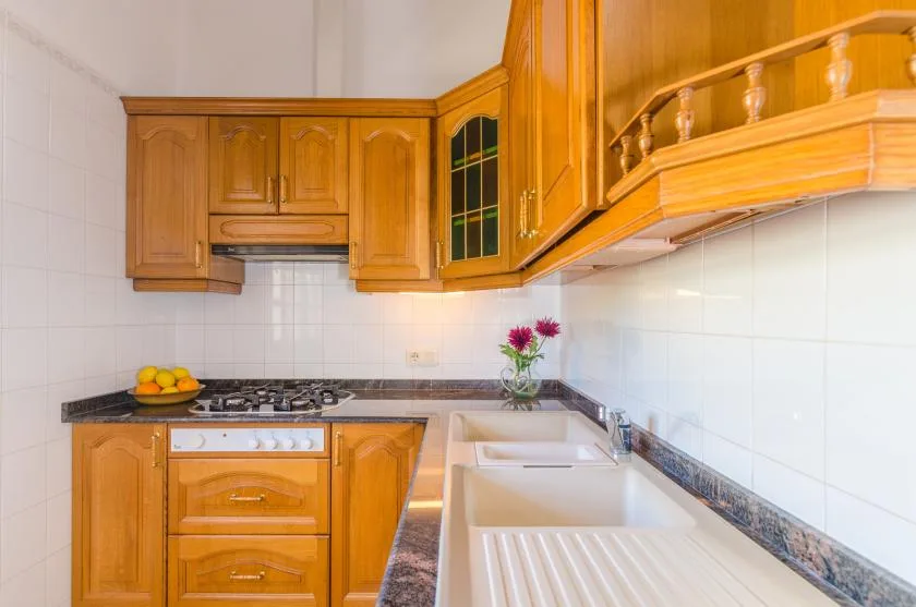 A bright kitchen with wooden cabinets, a dark countertop, and a white sink.