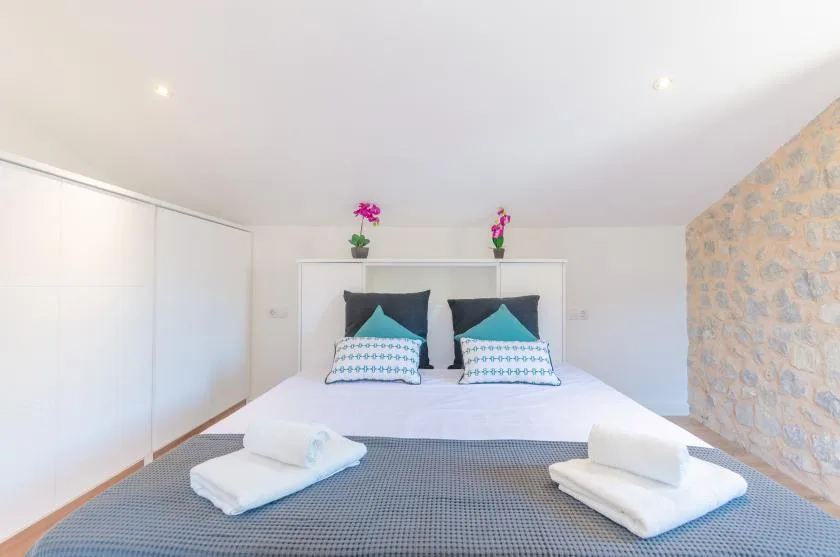 A bright bedroom with a neatly made bed and folded towels.