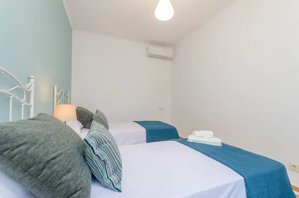 A bedroom with white bedding, teal blankets, and decorative pillows.