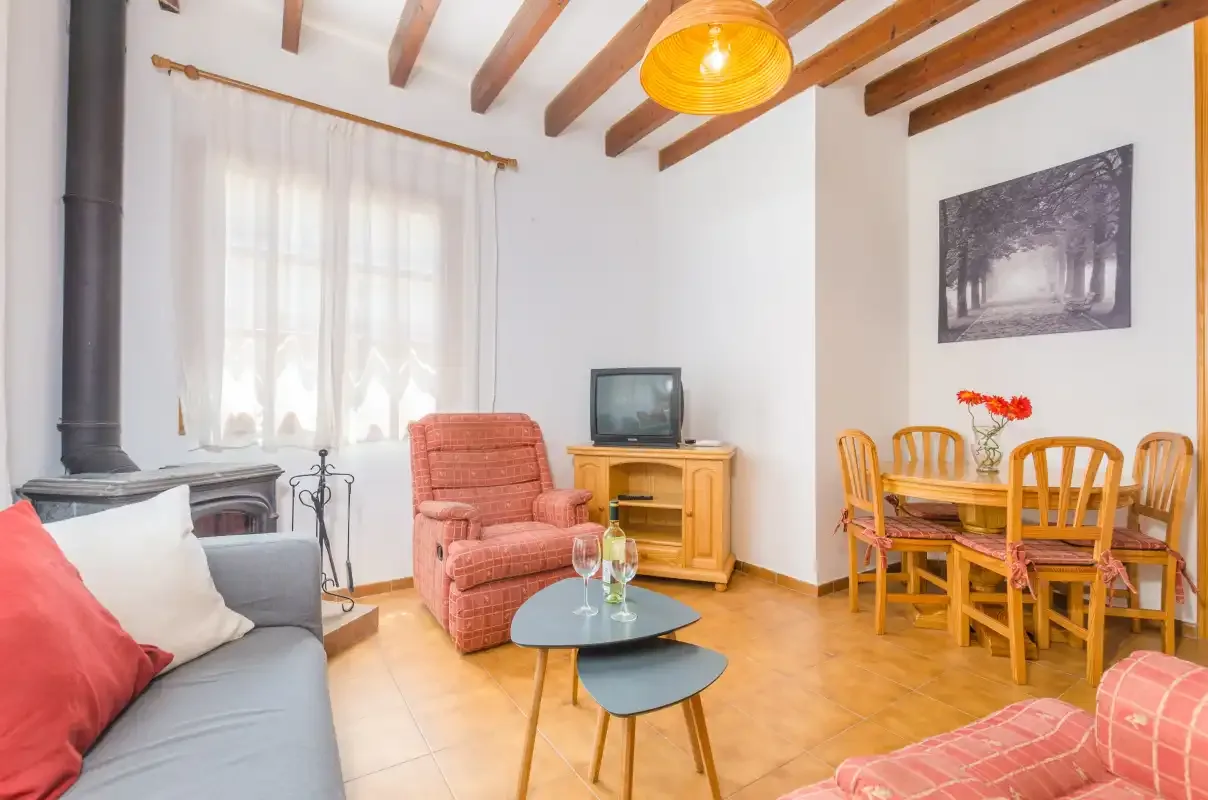 A bright living room with a dining table and seating beneath exposed ceiling beams.