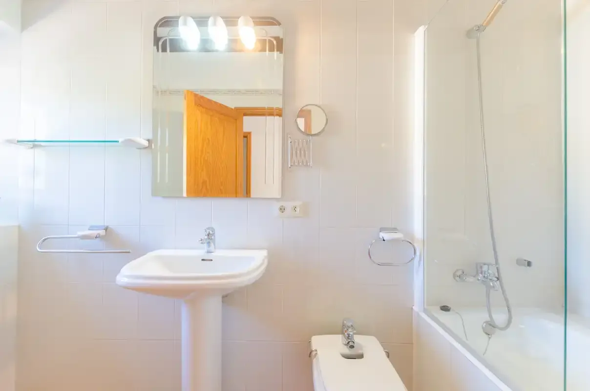A bright bathroom with a sink, mirror, and bathtub with shower.