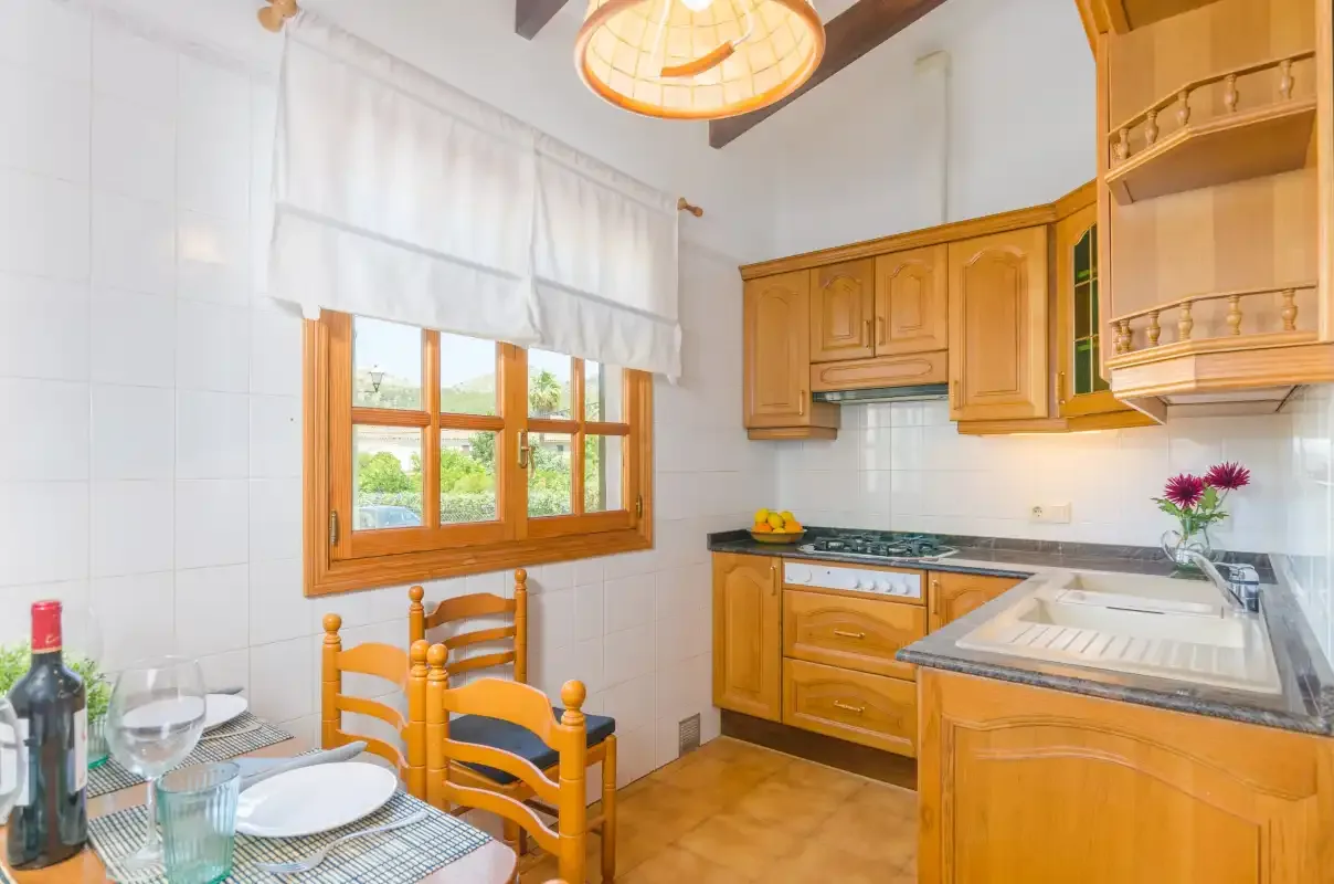 A kitchen with wooden cabinets, a sink, and a window overlooking greenery.
