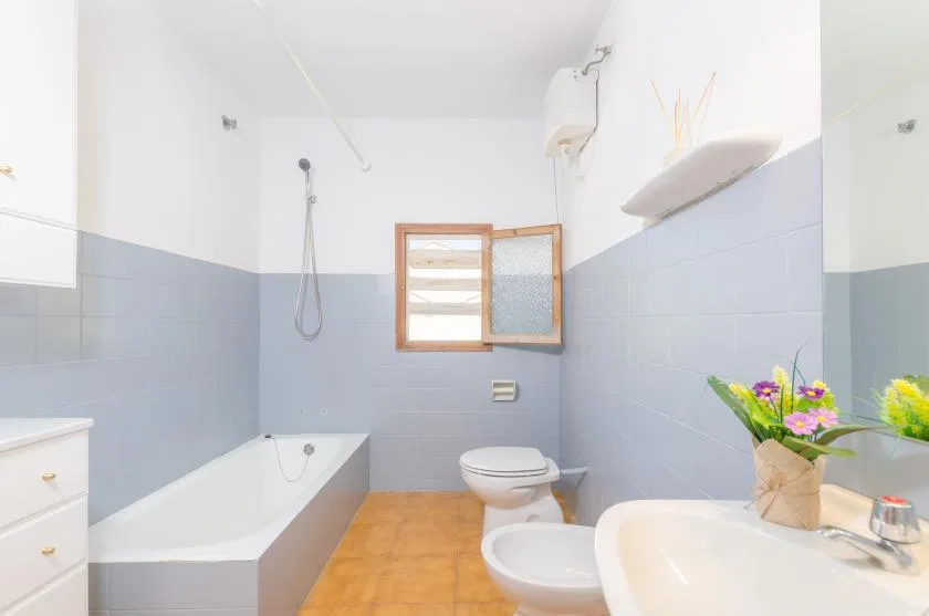A bathroom with a bathtub, toilet, and sink beneath a small window.