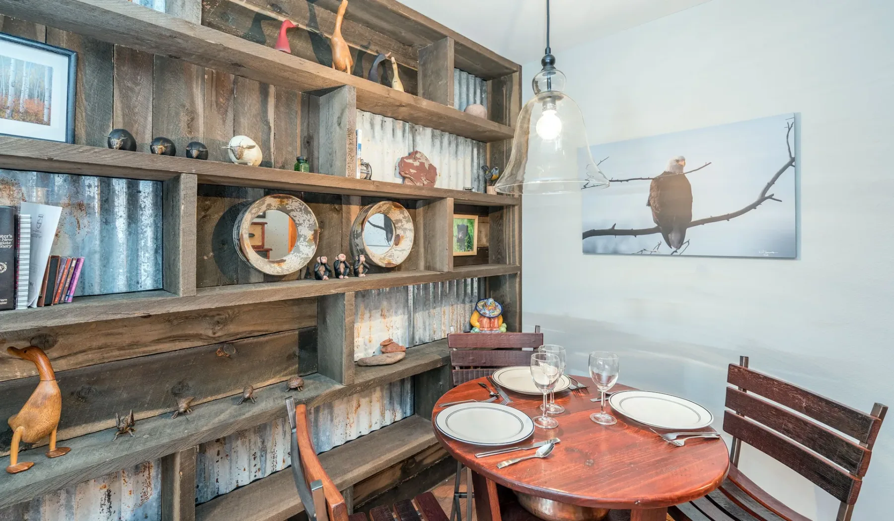 Un comedor con una mesa redonda de madera junto a una gran estantería.