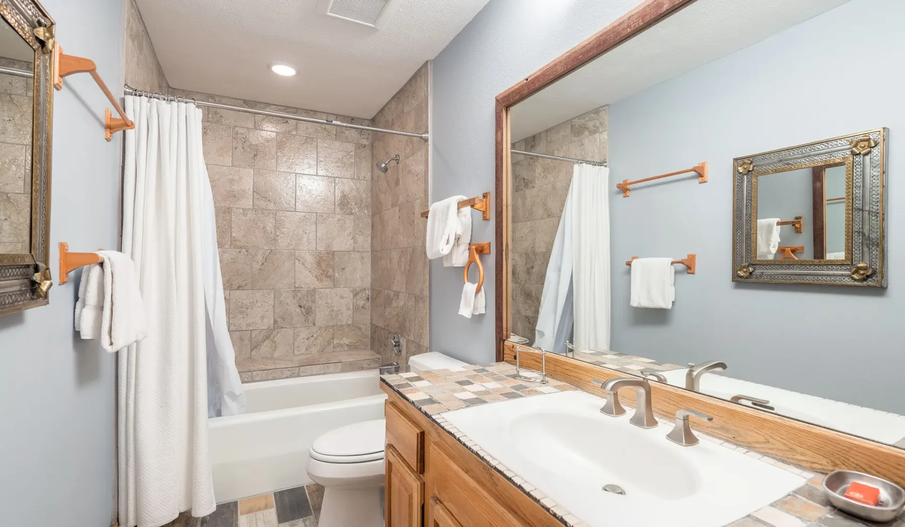 Un baño con lavabo, espejo y ducha detrás de una cortina.
