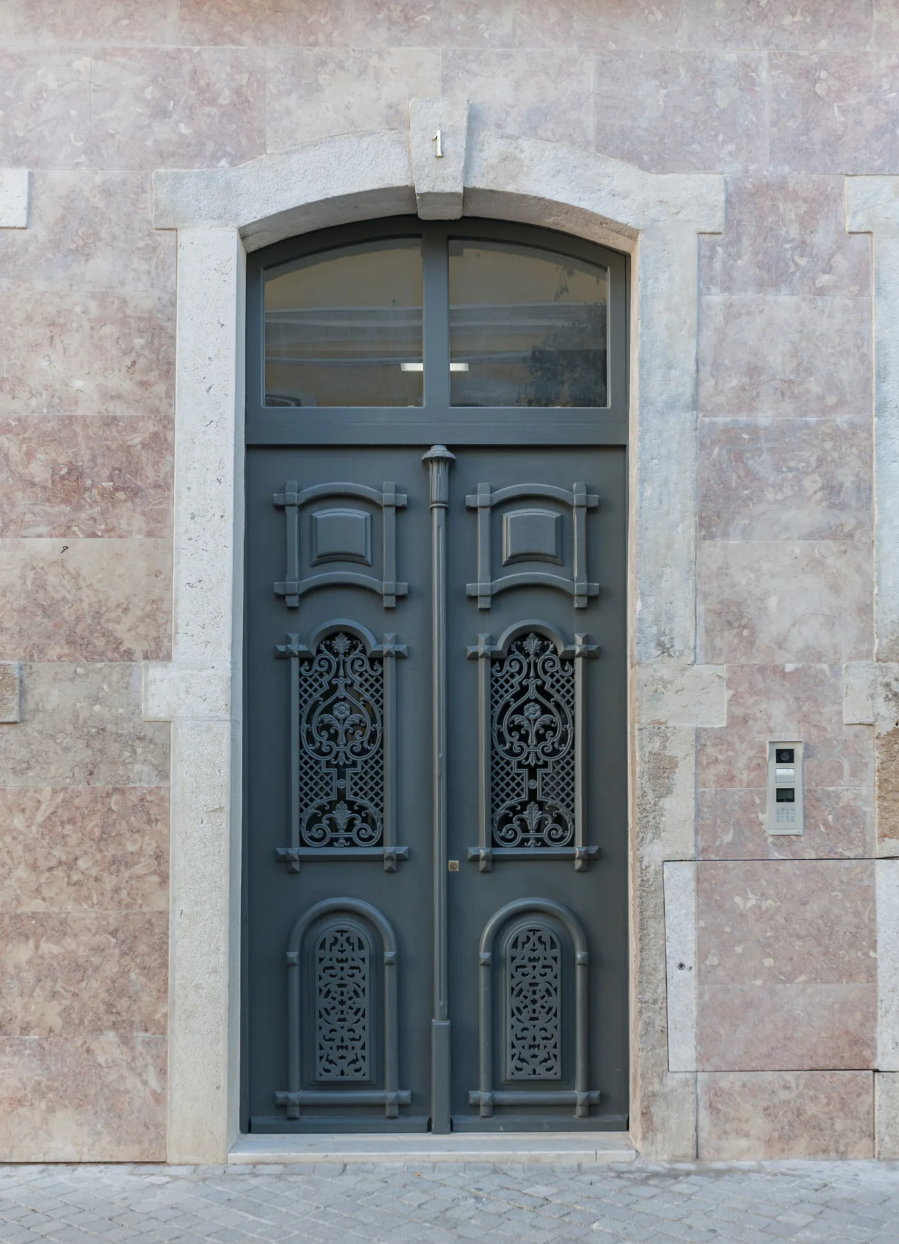 An ornate gray entrance door set into a pale stone facade.
