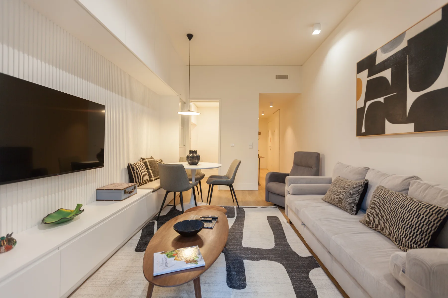 A bright living room with seating, a dining table, and abstract wall art.