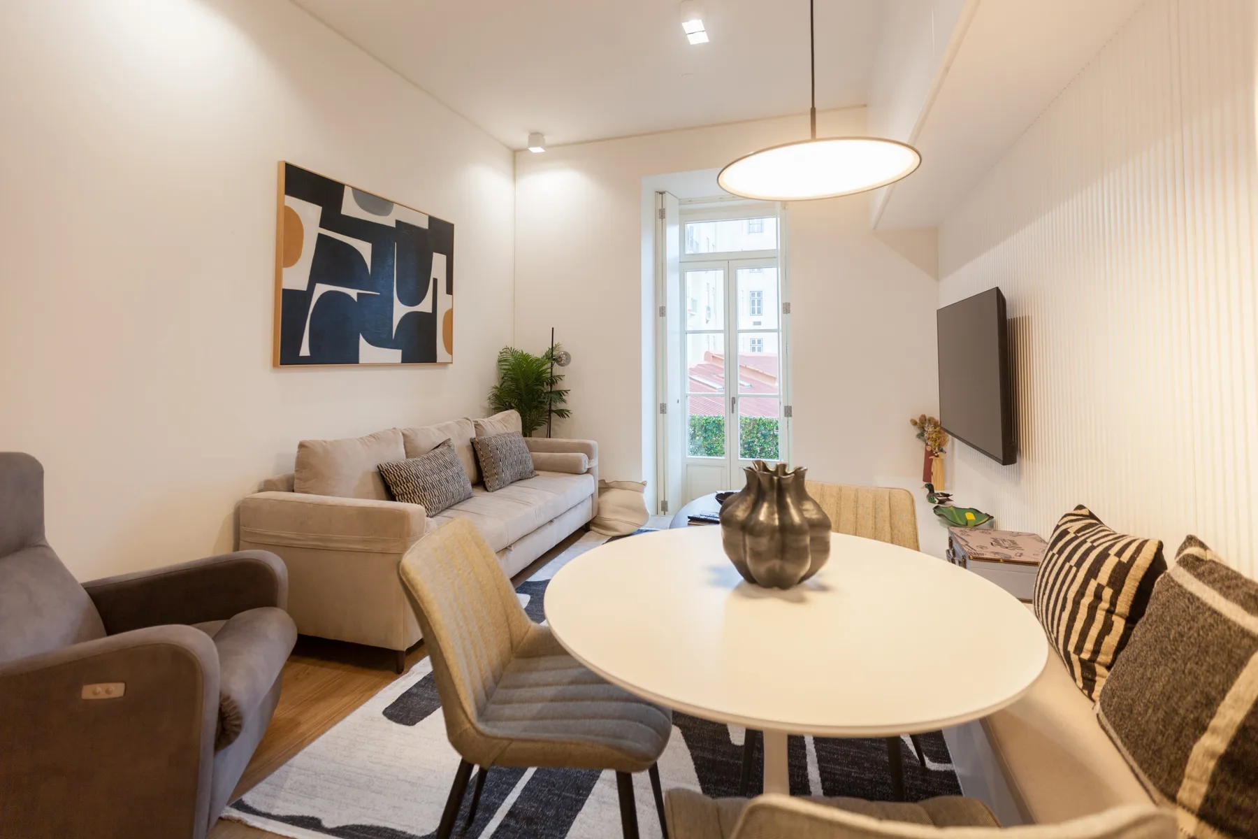 A bright living and dining area with seating around a white table.