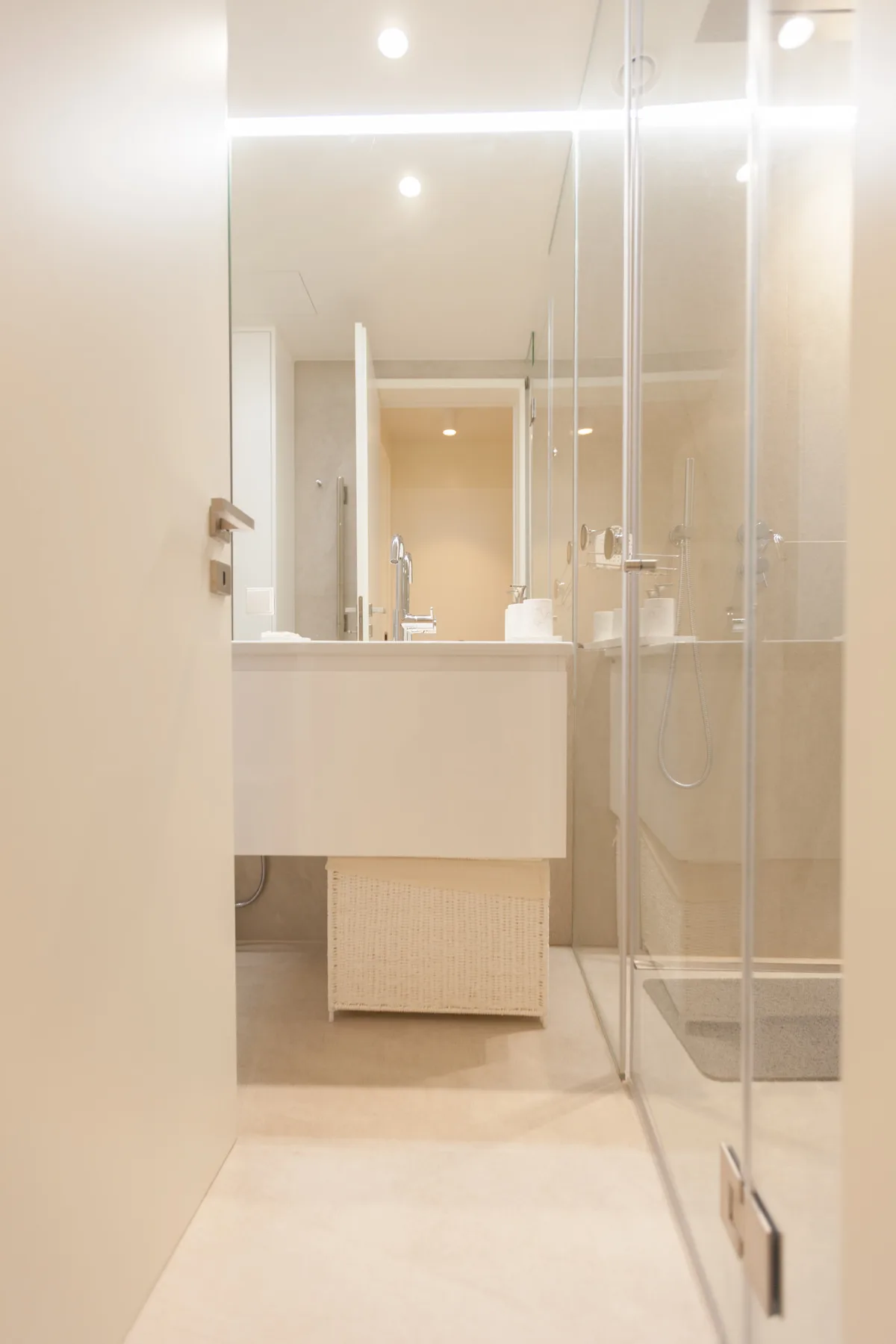 A bright bathroom with a sink, mirror, and glass shower.