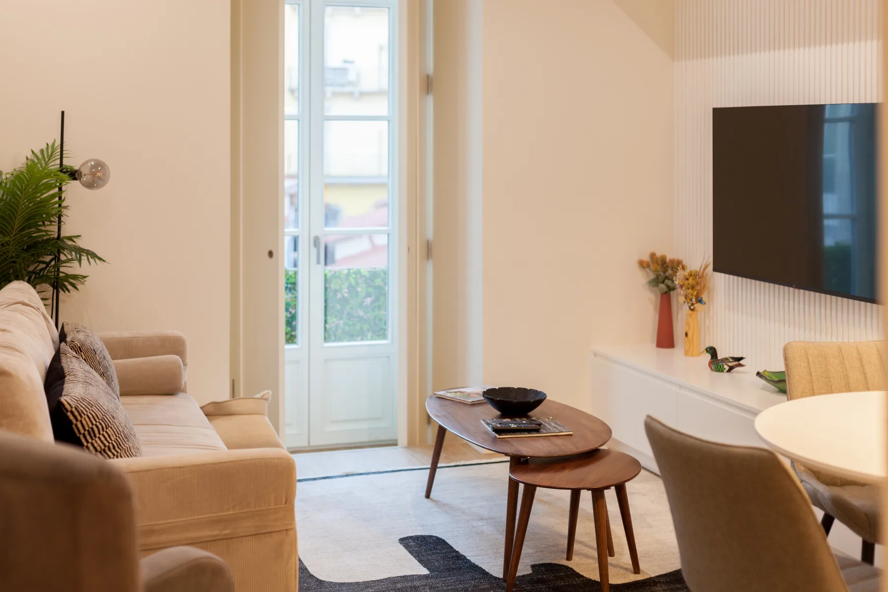 Una sala de estar luminosa con asientos, una mesa de centro y un televisor.