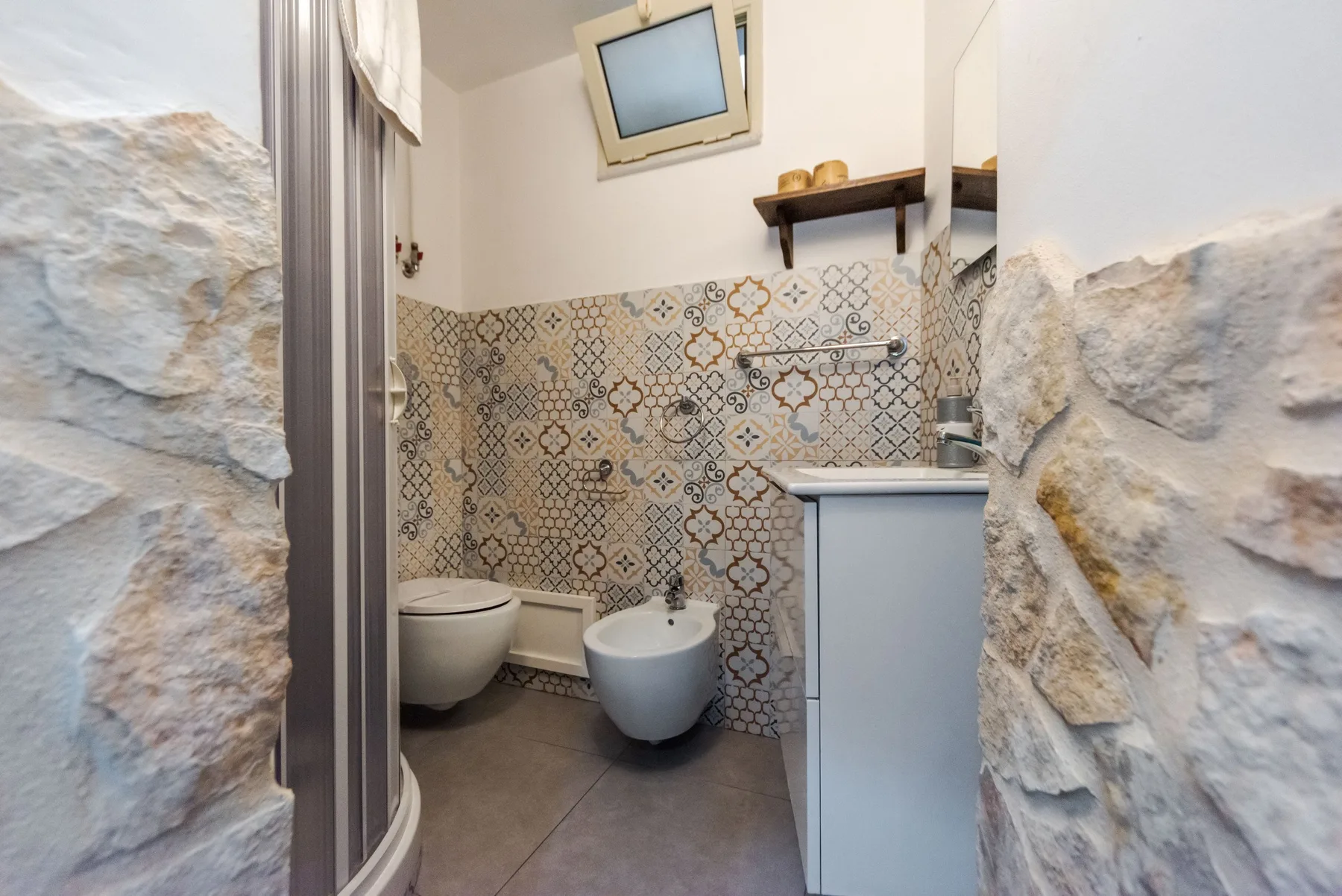 A tiled bathroom with a toilet, bidet, and curved shower enclosure.