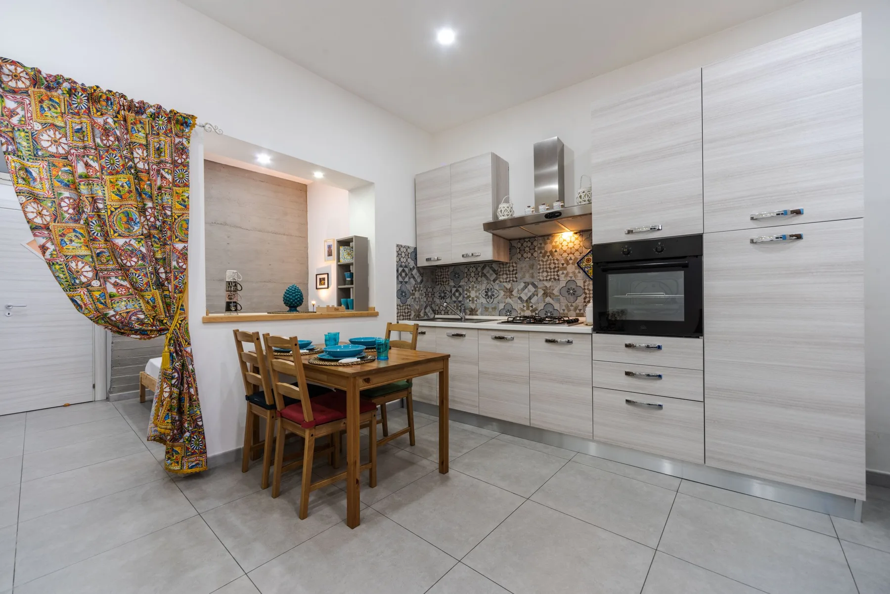 A modern kitchen with light cabinetry and a dining table.