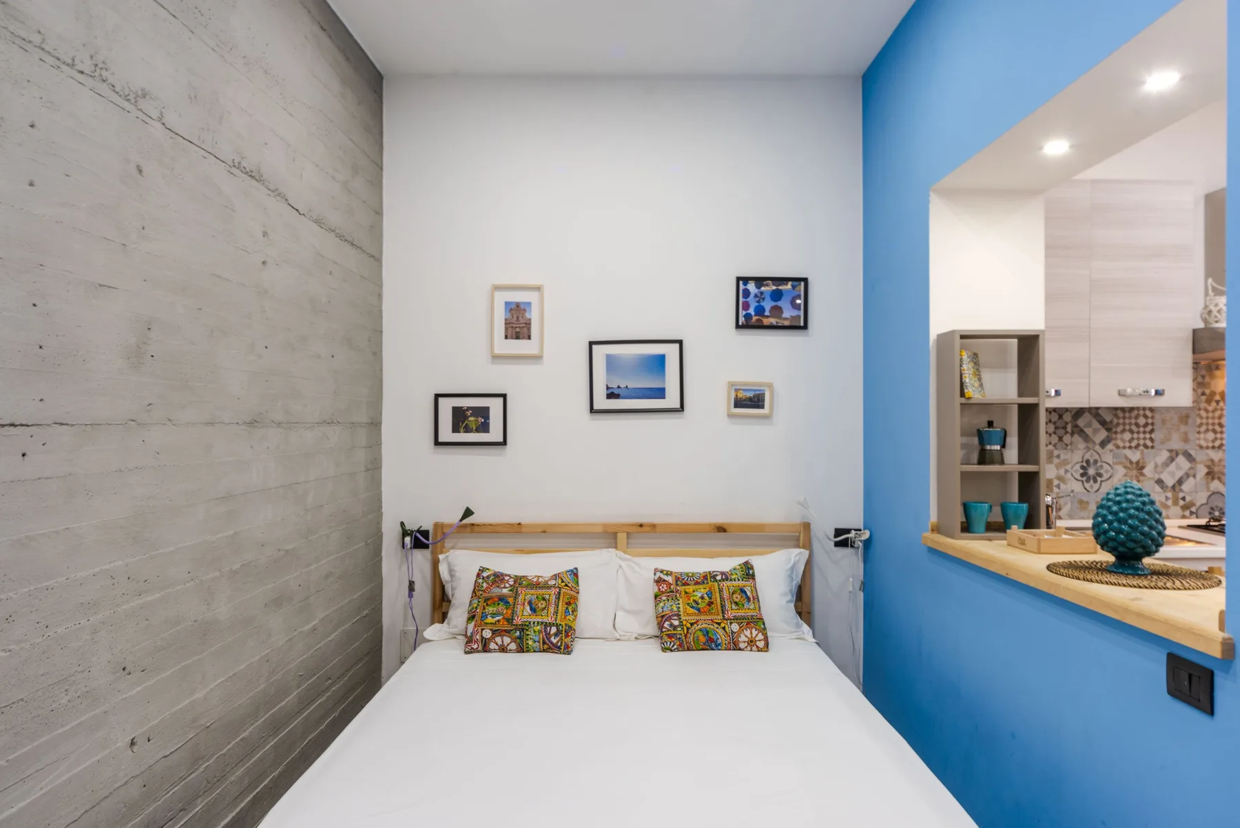 A bedroom with a neatly made bed and framed pictures above it.