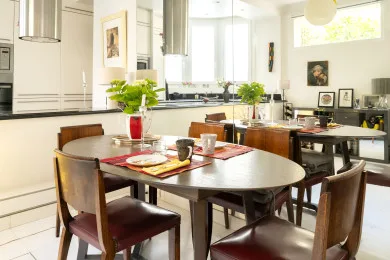 A bright kitchen and dining area with a set table and wooden seating.