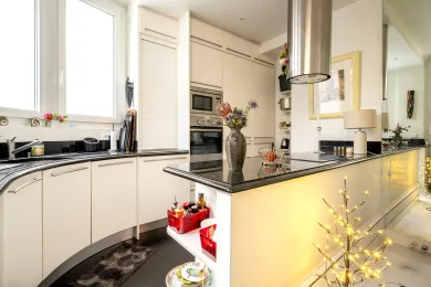 A bright kitchen with white cabinetry, dark countertops, and a central island.