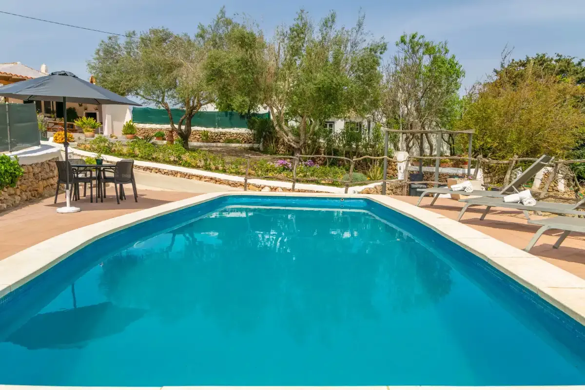 An outdoor swimming pool is surrounded by a paved patio and seating.