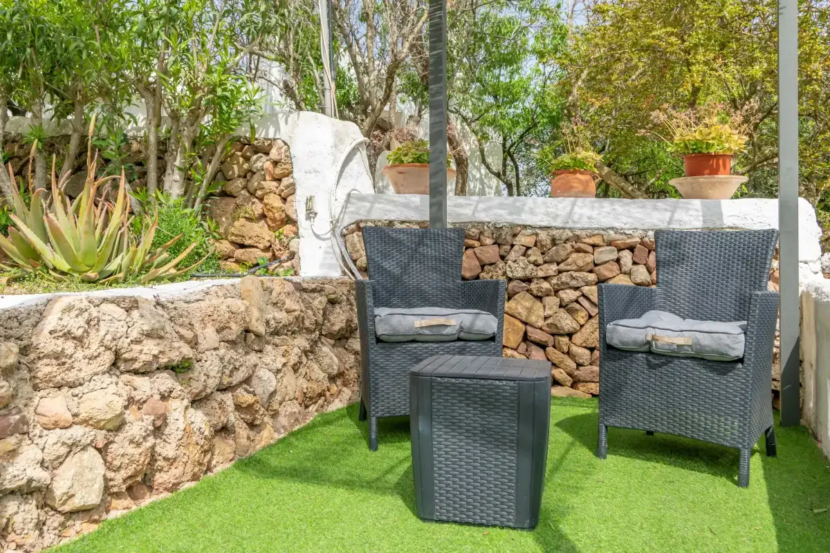Outdoor seating area with two chairs and a small table on artificial grass.