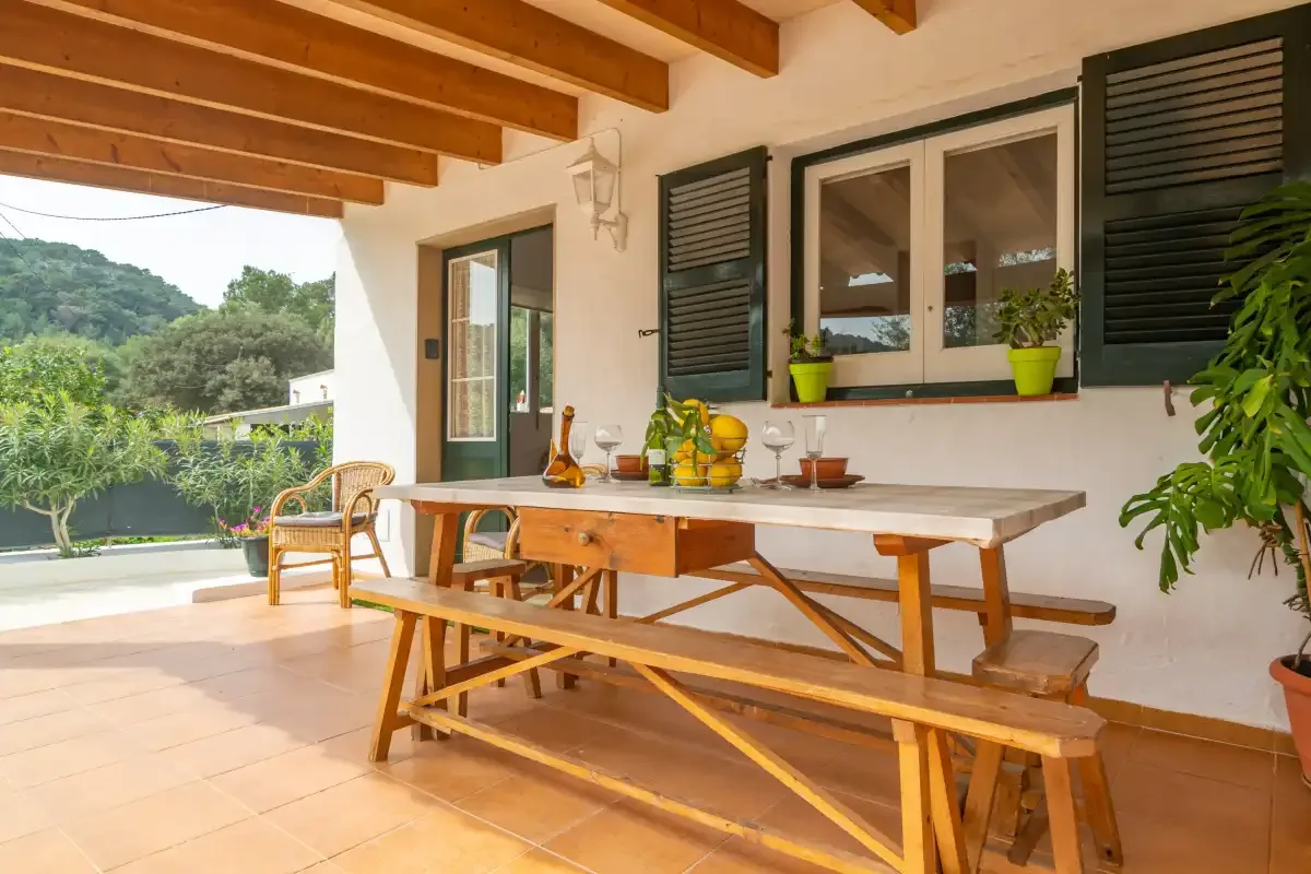 A covered outdoor dining area with a wooden table and seating beside the garden.