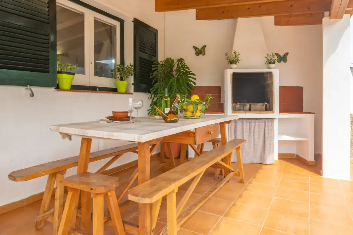 A dining area with a long wooden table and benches beneath exposed ceiling beams.