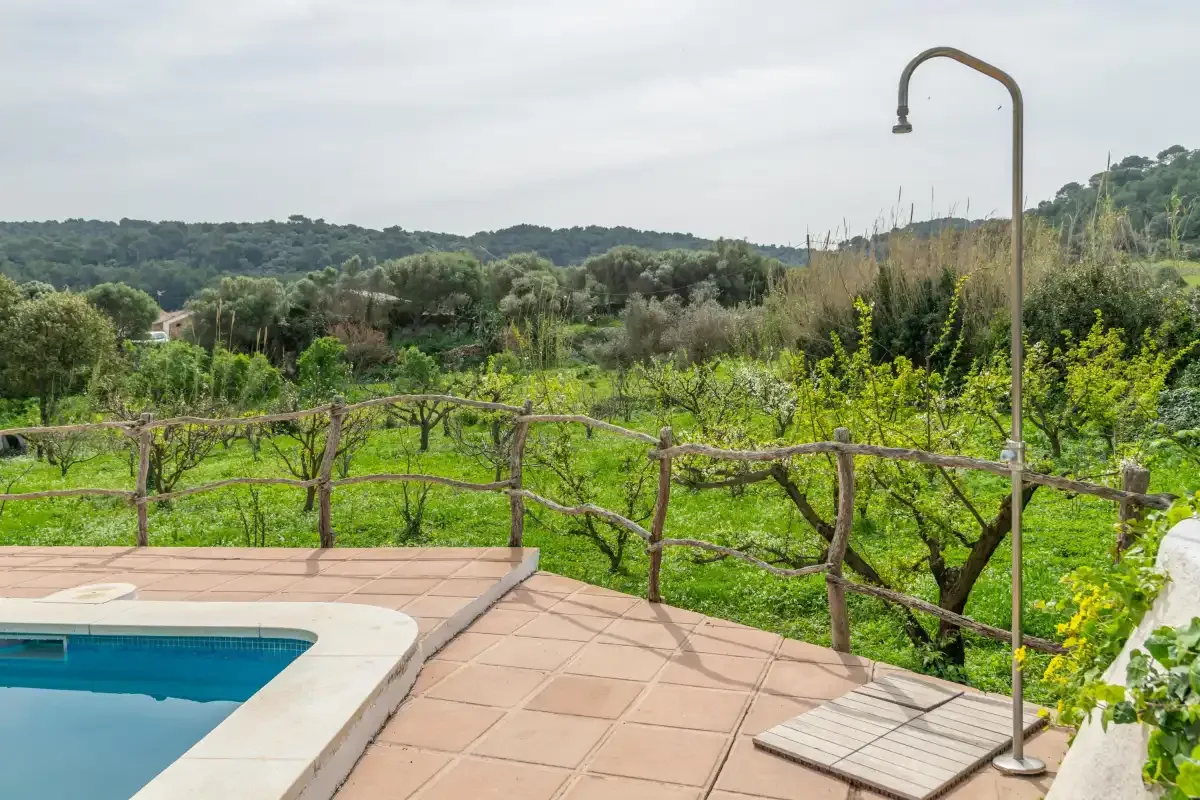 A tiled poolside patio overlooks a green countryside landscape.