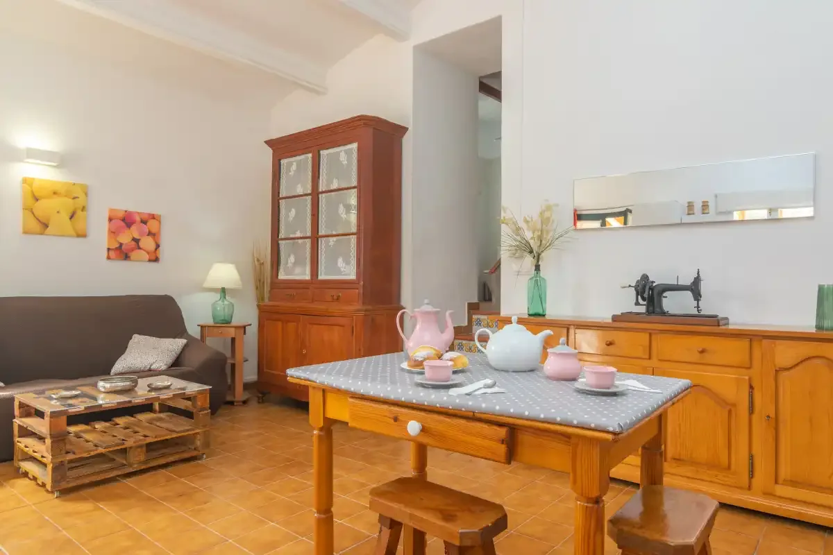 A dining area with a wooden table, tea service, and a sewing machine on the counter.