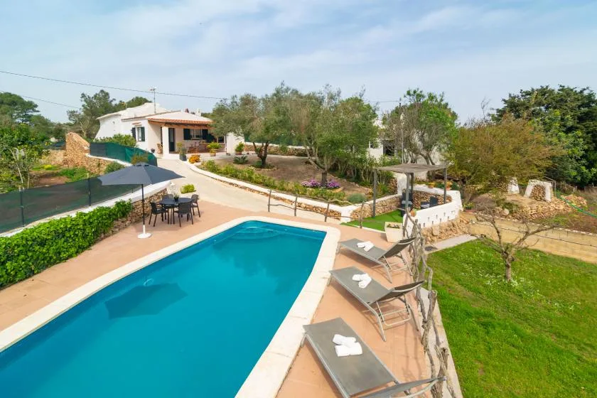 An outdoor swimming pool beside a landscaped garden and patio seating.