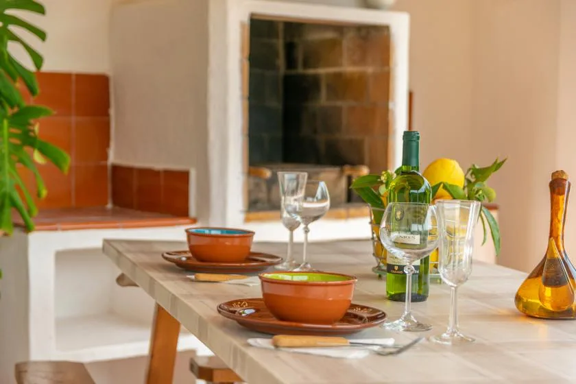 A dining table is set with bowls, wine glasses, and a green bottle.