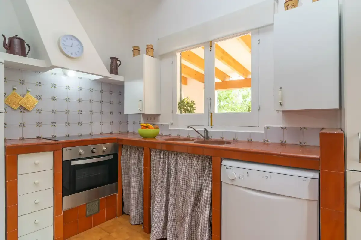 A bright kitchen with orange countertops and a window above the sink.