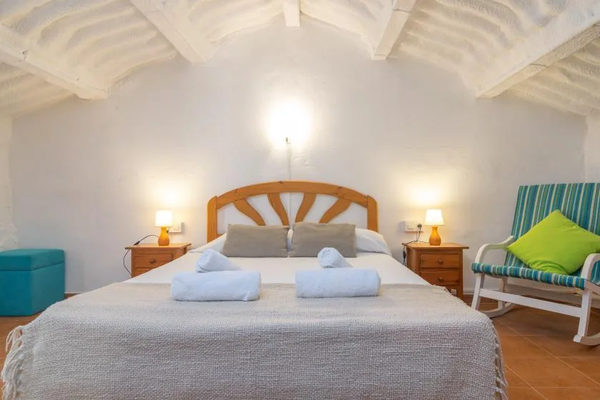 A bedroom with a bed, bedside tables, and a striped chair.