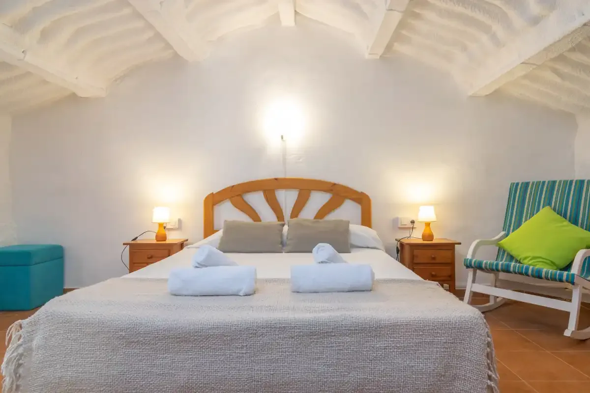 A bedroom with a bed, bedside tables, and a striped chair.