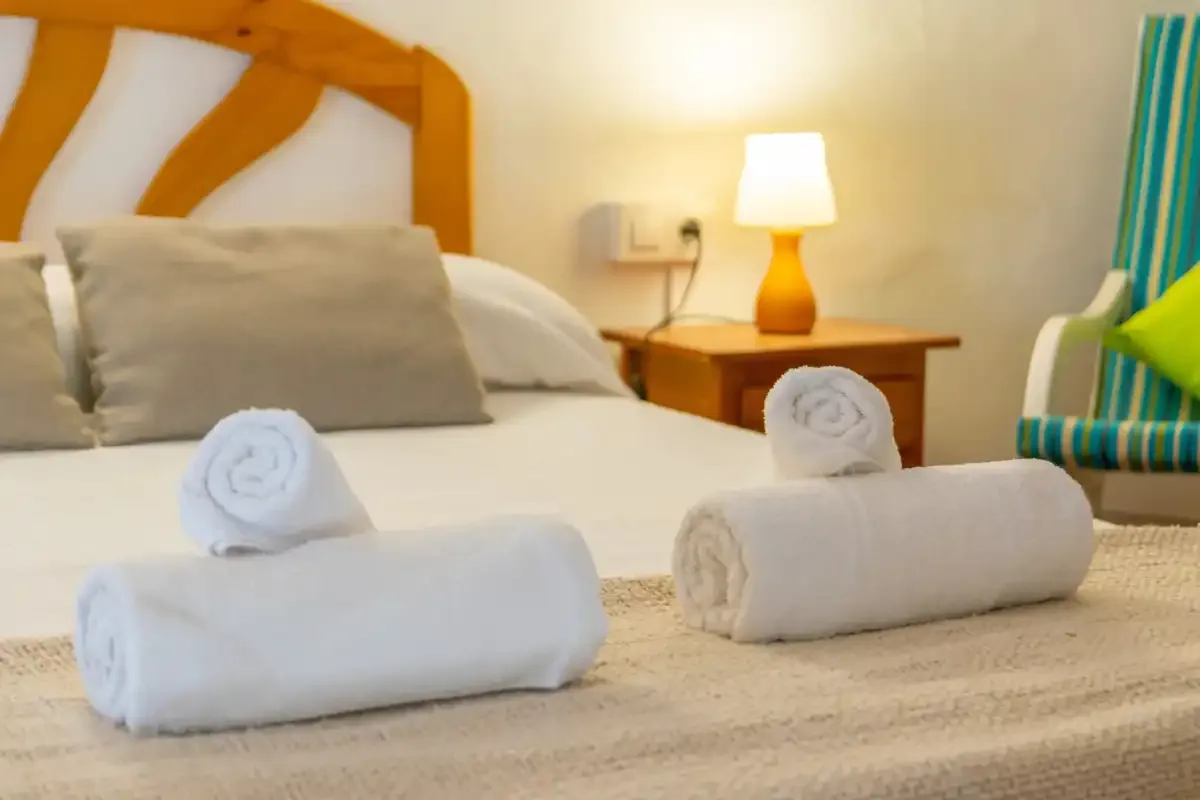 A bedroom with a neatly made bed and folded towels.
