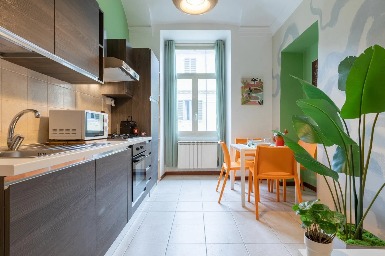 A kitchen and dining area with a counter, table, and orange seating.
