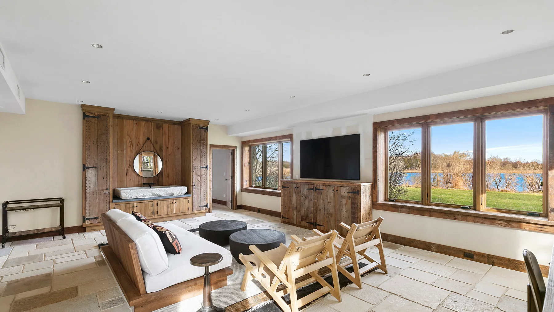Una sala de estar con asientos, un televisor y grandes ventanas con vista al exterior.