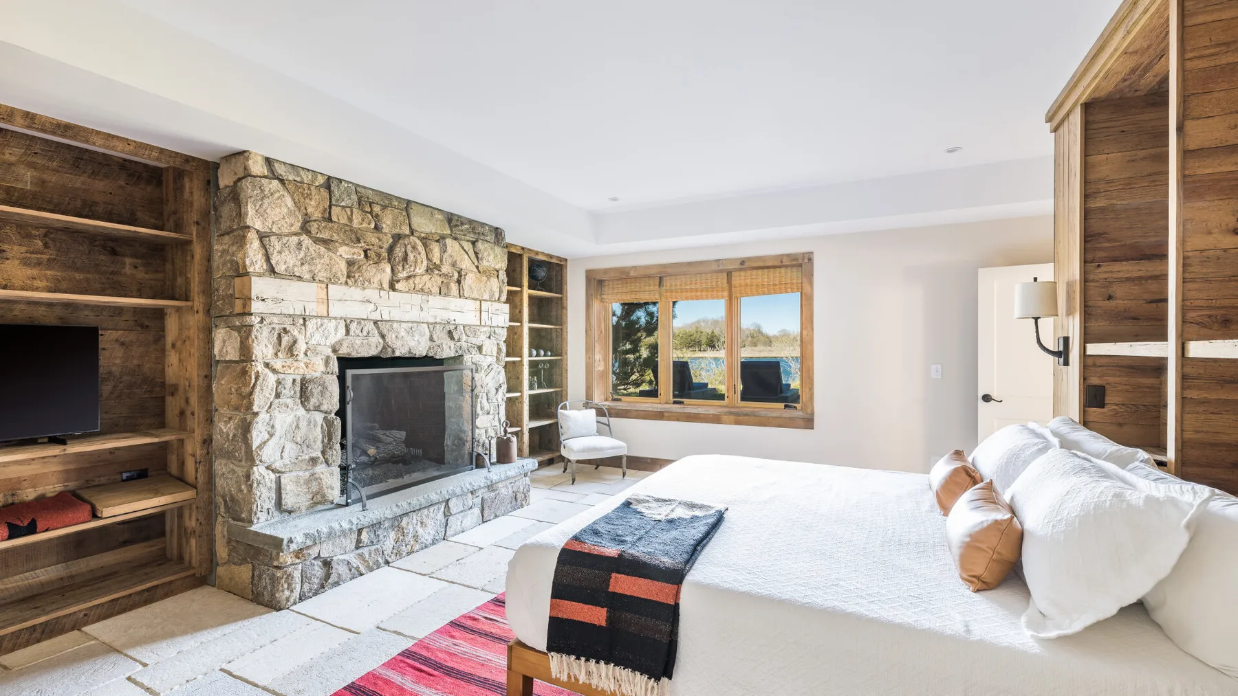 Un dormitorio con una cama grande, una chimenea de piedra y estanterías de madera.