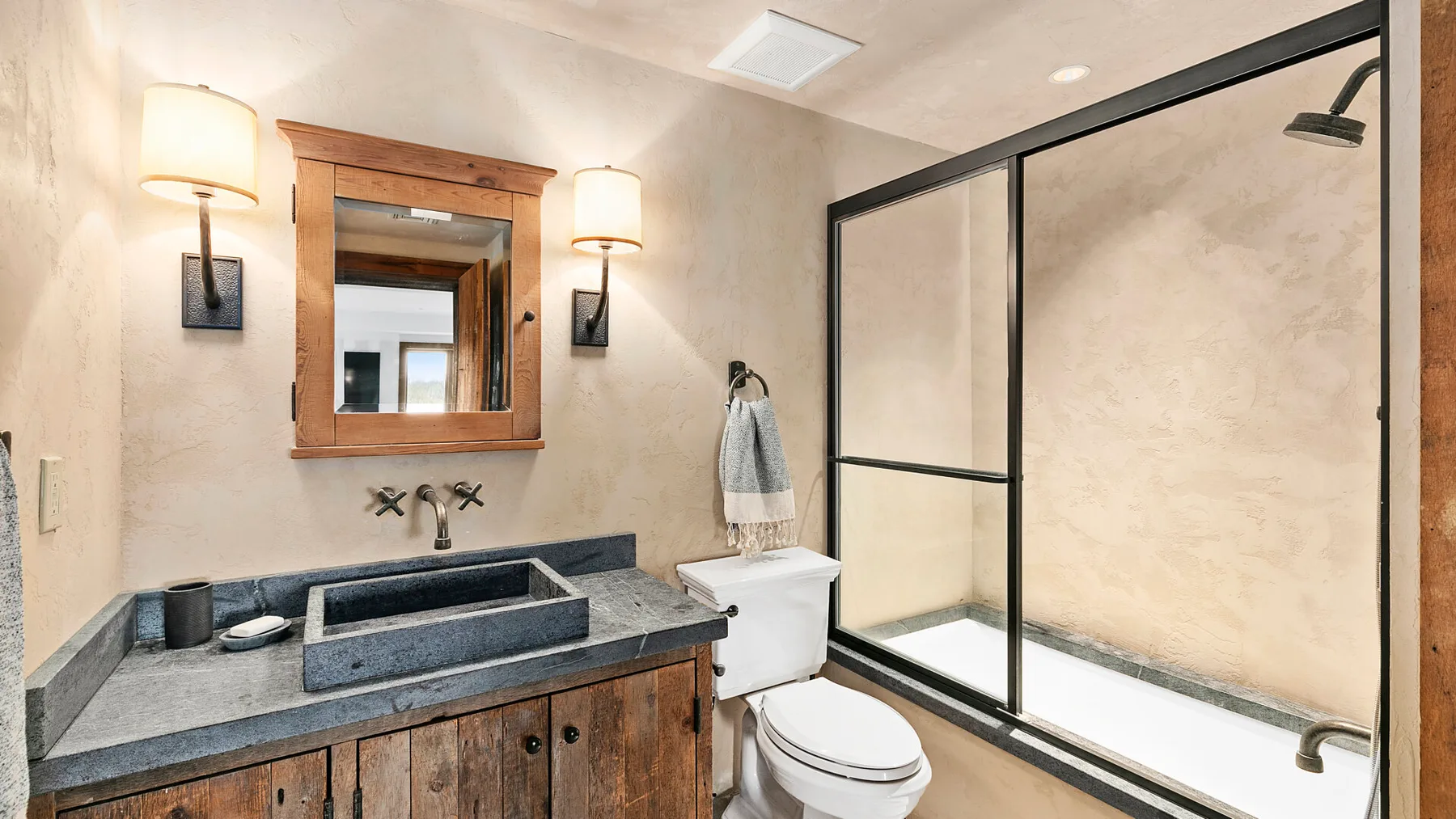 Un baño con lavabo, espejo y ducha con mampara de vidrio.