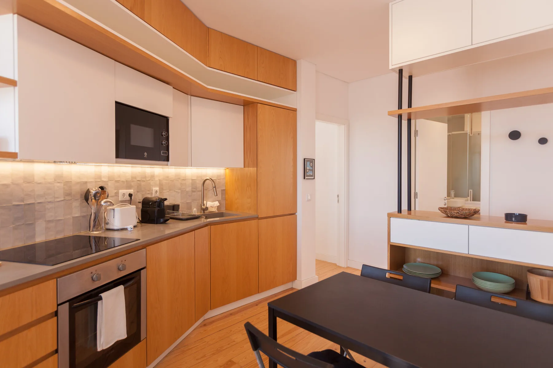 Una cocina moderna y comedor con gabinetes de madera y una mesa oscura.
